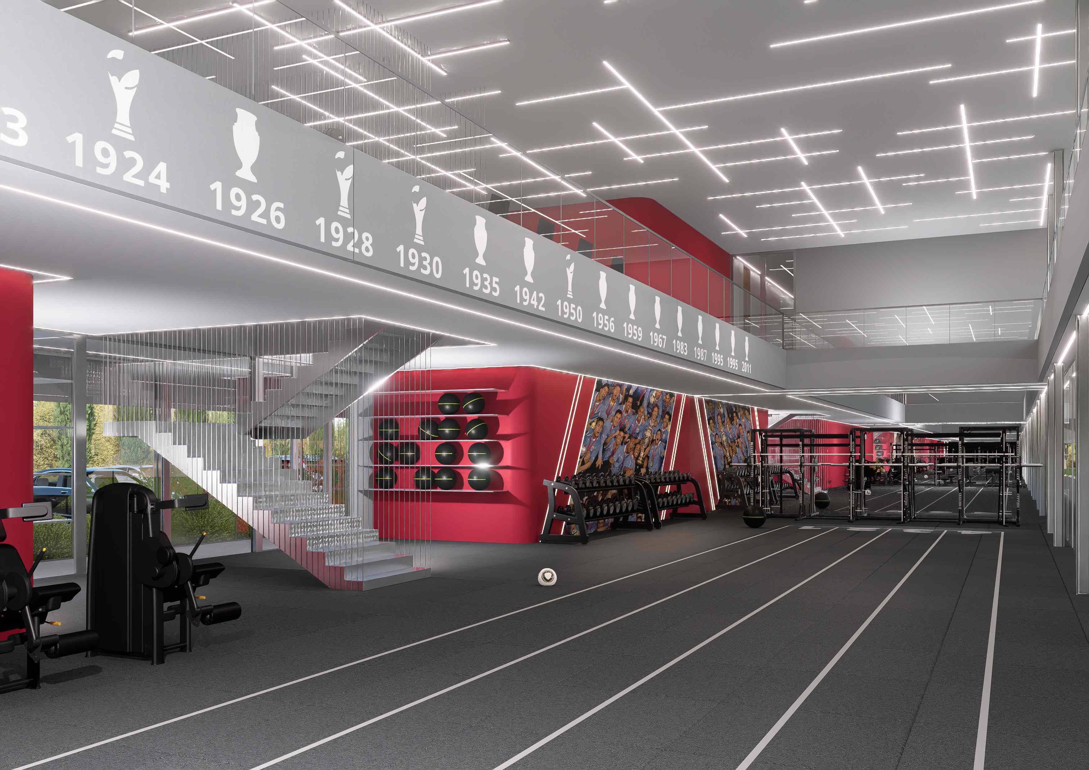Gimnasio de planta baja con pista de entrenamiento, escalera de vidrio y friso con los años de títulos