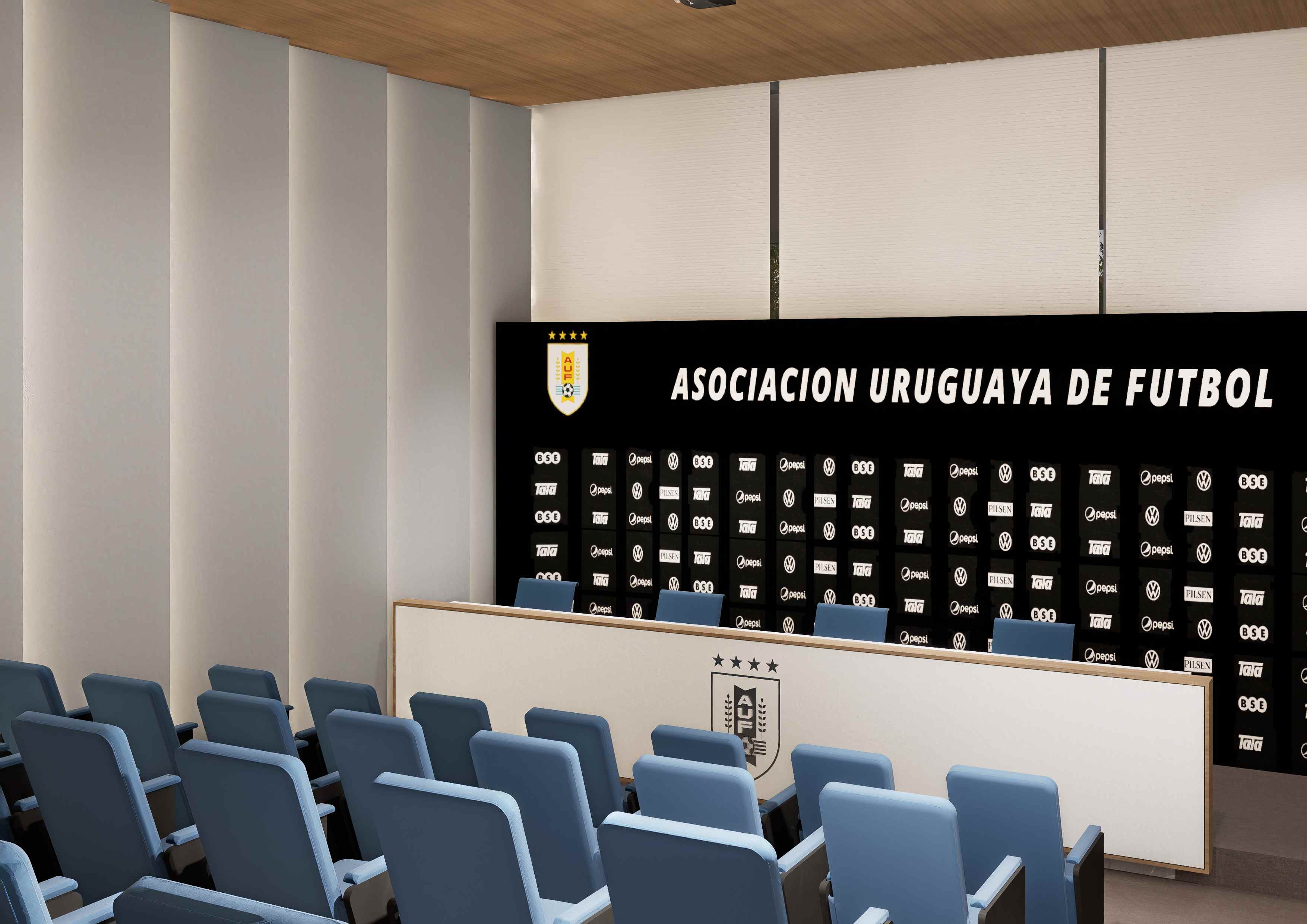 Sala de prensa con butacas celestes, mesa de conferencias y fondo institucional de la AUF
